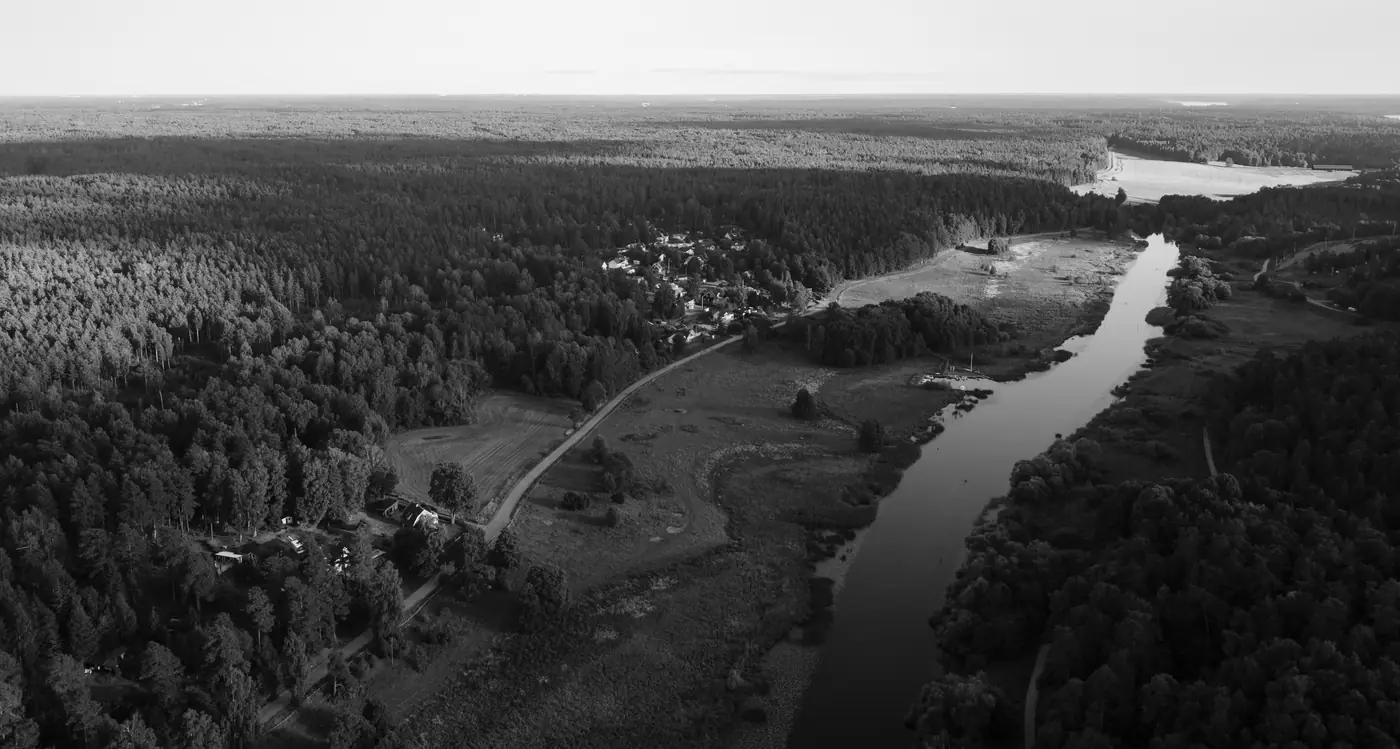 Flygbild över Fyrisån och byn Lugnet vid Uppsala, med skog, åkermark och bebyggelse