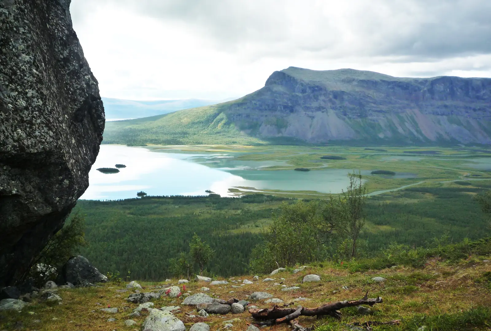 Rapadalen i Sarek: mörk klippa i förgrunden, deltat och fjällmassivet till höger